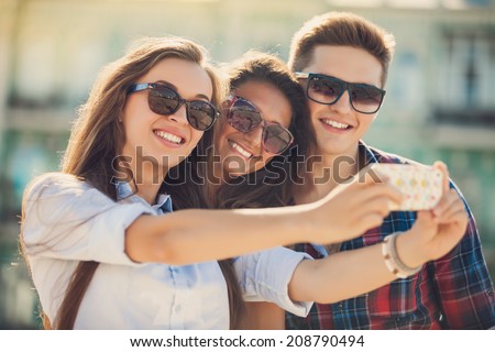 holidays and tourism, modern technology concept - beautiful friends taking picture in the city