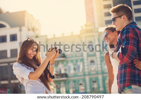 holidays and tourism, modern technology concept - beautiful friends taking picture in the city