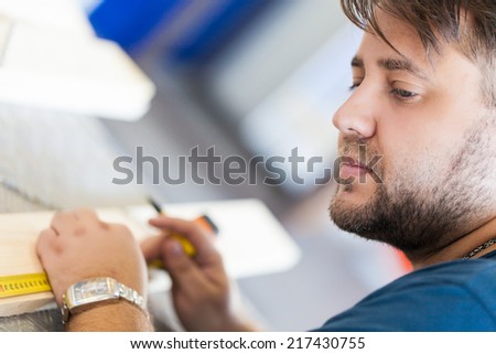 Close Up view of a carpenter using a straightedge to draw a line.