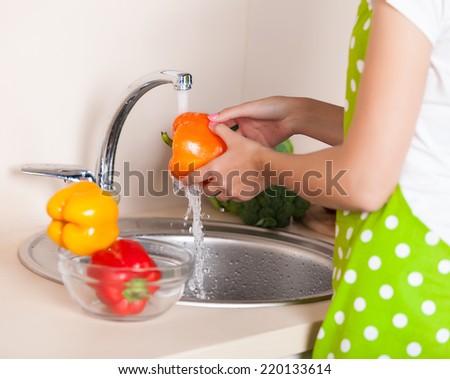 woman washing vegetables at kitchen