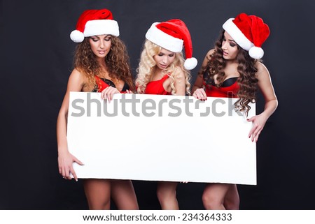 Group of cheerful santa girls hold the blank placard with copy text. Christmas greetings card