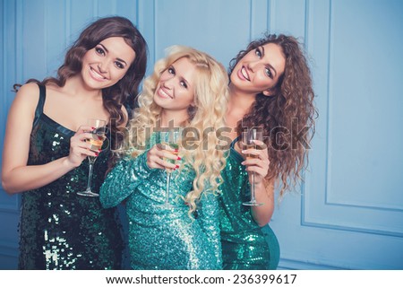 Three girls in evening dresses with champagne glasses - new year, celebration, friends, birthday concept