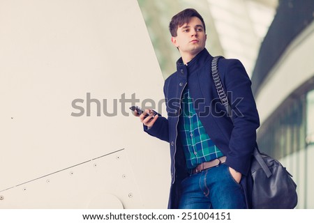 Young urban businessman with smart phone and leather bag