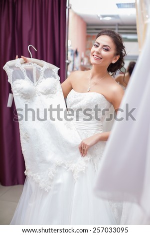 Young woman is choosing a wedding dress in the shop