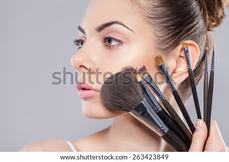 Beauty girl with makeup brushes. Perfect smooth skin.Applying makeup.Beautiful young woman holding different make up brushes