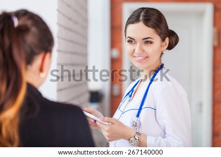 Smiling female doctor with patient writing prescription