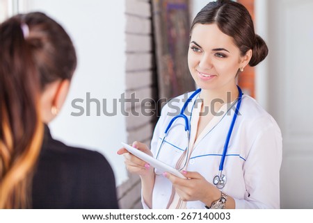 Smiling female doctor with patient writing prescription