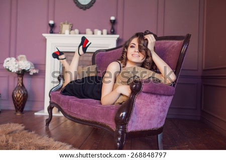 Beautiful luxurious woman on a purple vintage couch