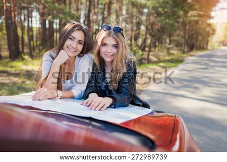 Happy friends on road trip reading a map on a summers day. Little holiday trip