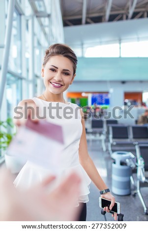 Attractive young woman giving passport and ticket at airport check-in counter