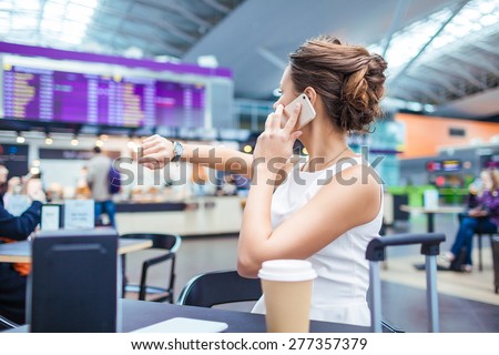 Young woman at international airport, drinking coffee while waiting for her flight. Female passenger at terminal, indoors.
