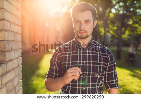 Portrait of handsome young man, charming hipster man posing outdoors, fashionable male model dressed causally