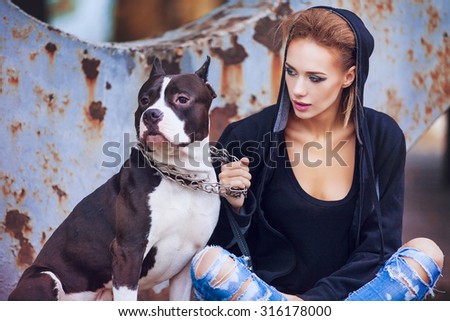modern punk fashion, portrait of a beautiful model posing with American staffordshire terrier over street background