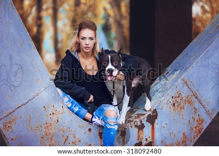 modern punk fashion, portrait of a beautiful model posing with American staff terrier over street background