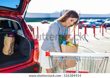 Woman after shopping in a mall or shopping center and driving home now with her car outdoor