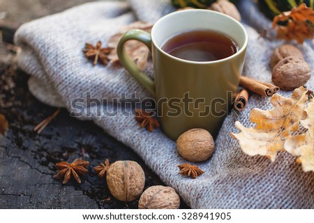 Cup of hot drink, knitting clothes, winter scarf on an old dry tree stump in the forest