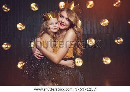 Beautiful princess mother and daughter in a gold crown. Warm toned
