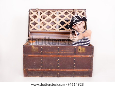 The boy in the image of a pirate, climbs out of the chest with treasures. a studio shot