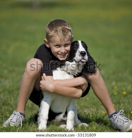 stock photo Preteen boy poses in a grass field with his Springer Spaniel 