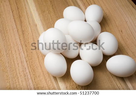 Baker\'s dozen of eggs in a pile on cedar planks.