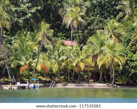 Waterfront property with boat at dock and lush tropical vegetation on an island in the Caribbean sea, Panama