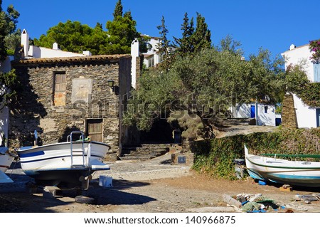 Old house with Catalan boat out of water and an olive tree in the Mediterranean village of Cadaques, Costa Brava, Catalonia, Spain