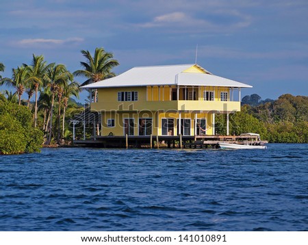 Tropical stilt house over the water with a boat at dock, Caribbean sea, Bocas del Toro, Panama