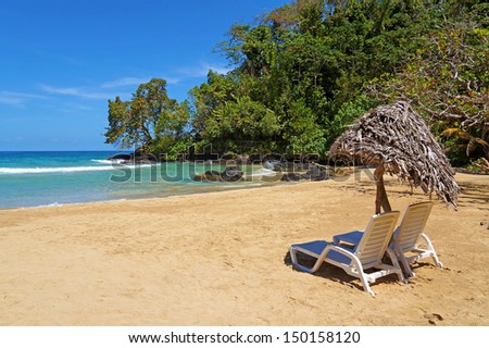 Lounge chairs with parasol on a beautiful tropical beach with sand,rocks and lush vegetation, Caribbean sea, Bocas del Toro, Panama