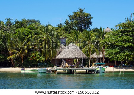 Beachfront eco resort with thatched hut over water and tropical vegetation, Caribbean sea, Bocas del Toro, Panama