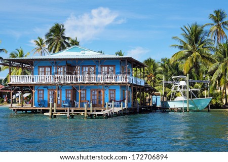 Beautiful tropical house on stilts over the Caribbean sea with a boat and coconut trees, Panama