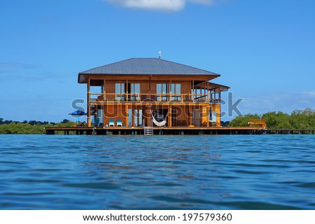 Wooden tropical home on stilts over water of the Caribbean sea, Panama, Central America