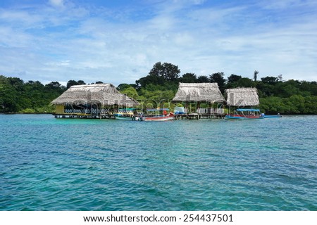 Tropical restaurant with thatched roof over the water and boats at dock, Caribbean, Bocas del Toro, Central America, Panama