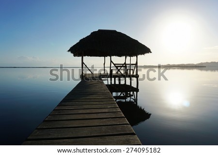 Dock with tropical hut over the water and calm sea surface with sunrise light, Caribbean, Panama, Central America