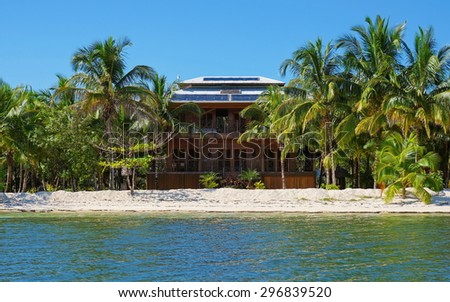 Off-grid beach house with solar panels on the roof and tropical vegetation on an island of the Caribbean sea, Panama