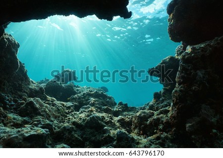 Underwater sunlight through water surface from a hole in a rocky ocean floor, natural scene, Pacific ocean, outer reef of Huahine, French Polynesia