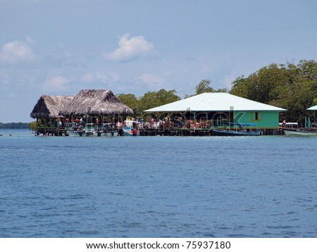 Over the water tropical bar restaurant with tourist and boat, Coral cay, Caribbean sea, Bocas del Toro, Panama