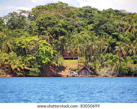 Coast of the Caribbean sea with house surrounded by lush tropical vegetation and cabin over the water, Bocas del Toro, Panama
