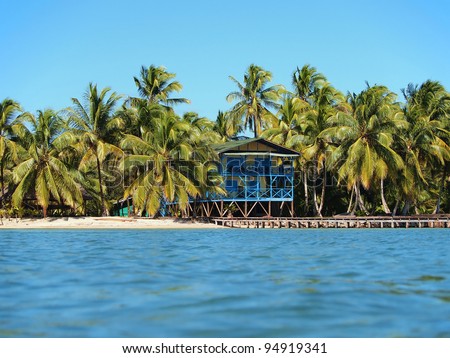 Small hotel on a tropical beach with lush coconut trees and a dock, Caribbean sea, Panama