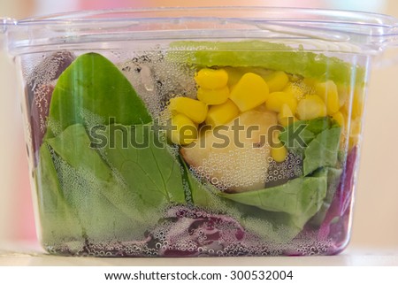 Healthy fruit salad in plastic package, side view, closed up