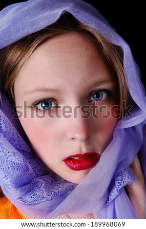 A beautiful young woman with blue eye\'s and a blue scarf around her head, isolated for black background.