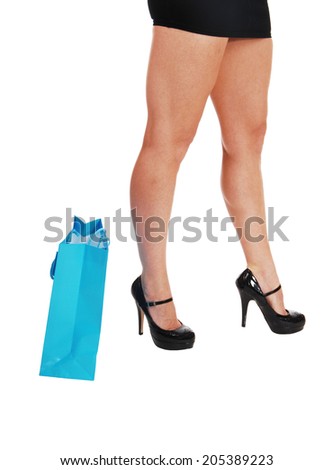 Long woman\'s legs in high heels standing isolated for white background with a blue shopping bag.