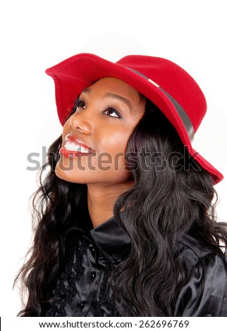 A lovely African American woman in a black blouse and long black curly\
hair with a red hat looking up, isolated for white background.