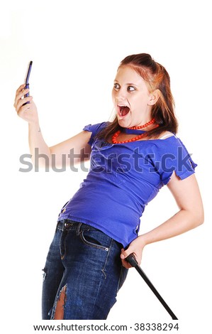 A pretty young girl with an suitcase and torn up jeans on a trip, holding up her cell phone and is very surprised and happy, on white background.