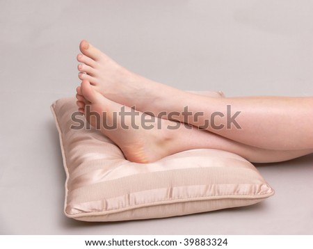 Girl is resting her bare feet on a cushion.