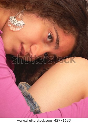 An pretty young girl, sitting on the floor and resting her head on her knees, in an denim mini skirt for white background.