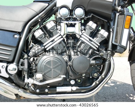 A very clean 4 cylinder motorcycle engine on a parking lot.