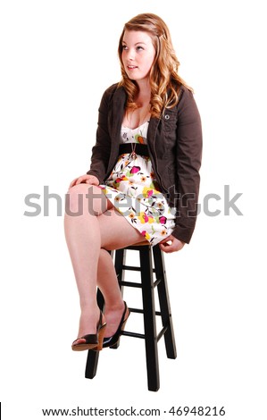 Young, lovely girl in a short dress and jacket, sitting on a bar chair in high heels and nice blond hair for white background.