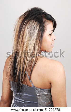 A portrait of a pretty and young Cambodian woman from the back and she turns her head to the side, on light gray background.