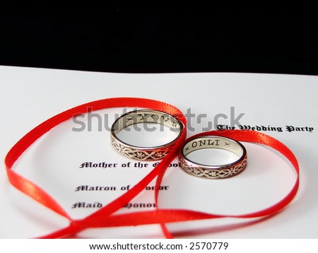 wedding rings on ceremony program, wrapped in a ribbon heart