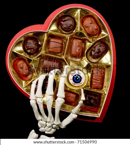 skeleton hand selecting an eyeball from a valentine\'s box of chocolates, isolated on black